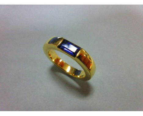 A contemporary iolite ring by Quinn, the rectangular step cut iolite tension set horizontally in a uniform plain chunky band 