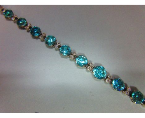 A blue zircon and diamond bracelet / necklace, composed of fifteen graduated round cut blue zircons in an articulated chain a