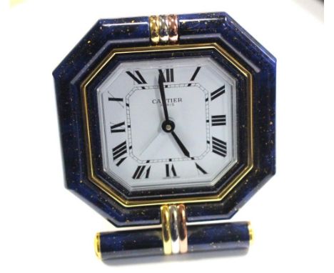 By Cartier - a brass cased travel alarm clock, with blue enamel and three tone gold plated octagonal bezel with white dial pr