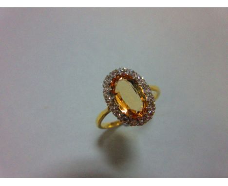 A topaz and diamond cluster ring, the oval cut light orange-brown topaz claw set in a border of sixteen single cut diamonds t