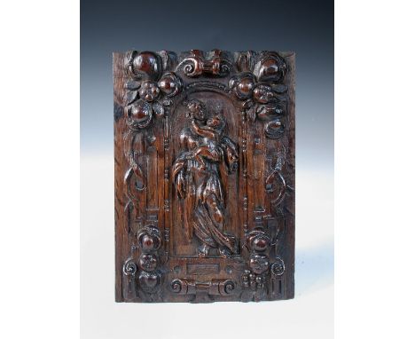 An 18th century North European relief carved oak panel, depicting the Madonna and Child within an archway to a surround of fr