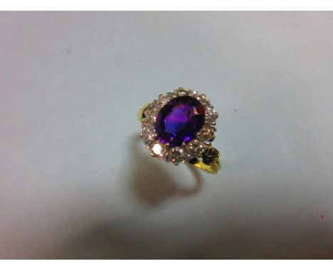 An amethyst and diamond cluster ring, the oval mixed cut rich purple amethyst claw set in a border of ten round brilliant cut