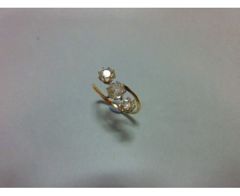 A three stone diamond ring, the three old cushion cut diamonds claw set in a diagonal line to a fine crossover shank, unmarke
