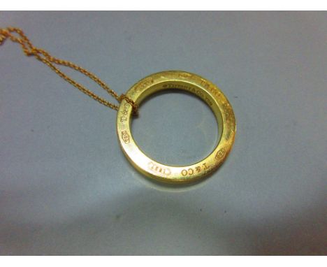 A Tiffany gold ring pendant and chain, the solid ring, diameter 2.6cm, with concave edge, and engraved all around on both sid