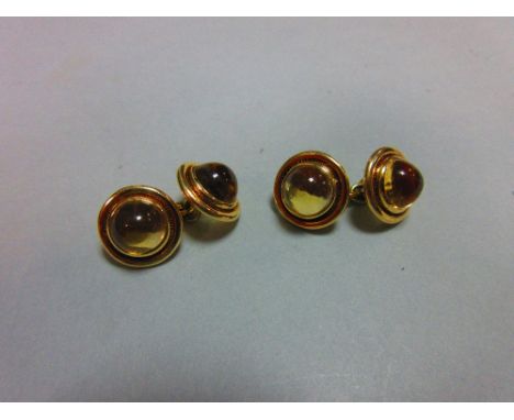 A pair of citrine set double ended cufflinks, each end with a round cabochon pale gold citrine collet set to a polished borde