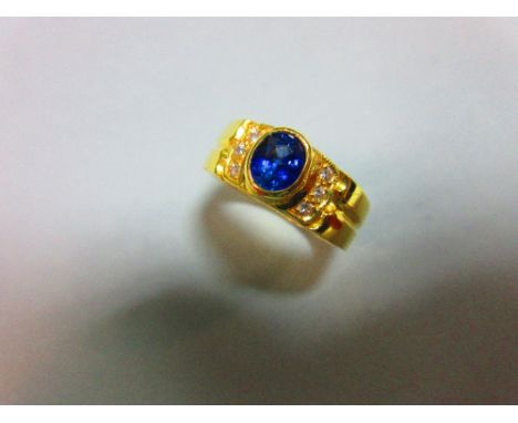 A sapphire and diamond ring, the oval cut intense blue sapphire in a raised collet between lines of small round brilliant cut