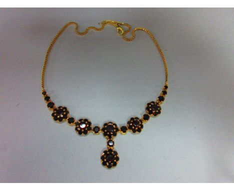 A Bohemian garnet cluster necklace, composed of five flowerhead clusters of round cut garnets, suspending from the centre ano