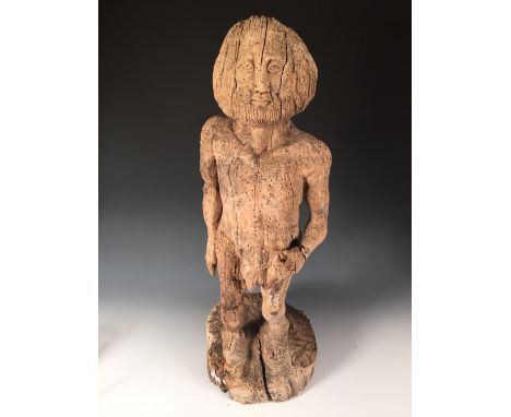 A Mediaeval style carved wood figure, possibly of Adam, the bearded figure naked with his left hand on his hip, he stands on 