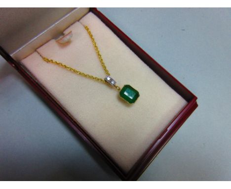 An emerald and diamond pendant set in 18ct gold, with chain, the emerald cut emerald collet set and suspended from a bale set