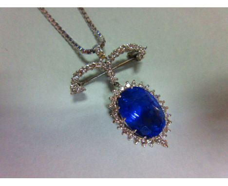 A sapphire and diamond pendant / brooch with white gold chain, the jewel designed as a large oval cut light blue sapphire, es