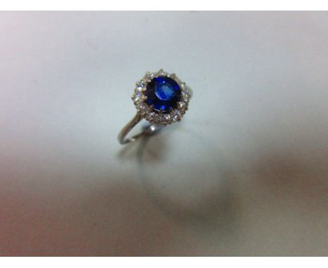 A sapphire and diamond cluster ring, the round cut sapphire in a border of old variously round cut diamonds, all claw set to 