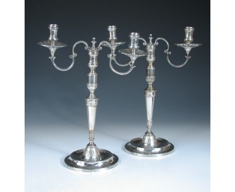 A pair of continental metalwares candelabra, unmarked, each raised from a circular foot with chased stiff leaf decoration to 