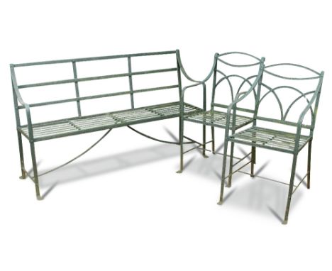 A Regency wrought iron strapwork garden seat, painted green and two similar strapwork chairs on moulded lion paw feet (3) Ben