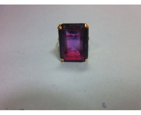 A synthetic colour change sapphire ring, the large step cut stone appearing blue in daylight and purple in artificial light, 