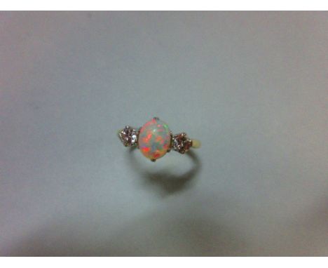 An opal and diamond three stone ring, the oval cabochon opal claw set between two round brilliant cut diamonds, in white to a