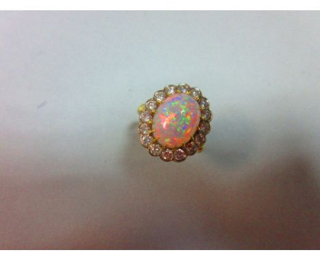 An opal and diamond cluster ring, the oval cabochon opal, displaying a rainbow range of fire, claw set to a scalloped edge bo