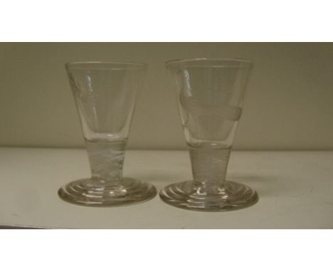 A pair of early 19th century firing glasses, the conical bowls engraved with stags' heads and peacocks, the opaque twist stem