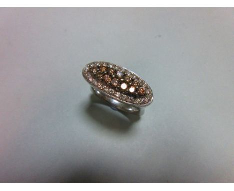 A diamond and coloured diamond pavé set ring, of horizontal elongated oval outline with a central navette of fancy smoky brow