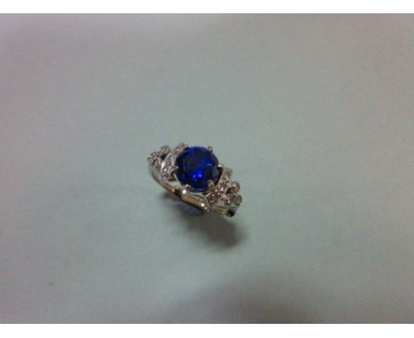 A sapphire and diamond ring, the round cut royal blue sapphire between shoulders with curved bands set with diamonds then fur