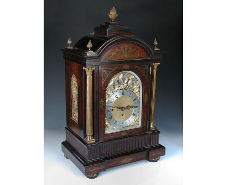 An imposing Victorian rosewood and brass inlaid chiming clock, the breakarch case with brass pineapple finials above arched b