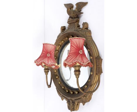 A Regency style gilt mirror, the top crested with an eagle on a rocky crag, between foliate scrolls, the glass surrounded by 