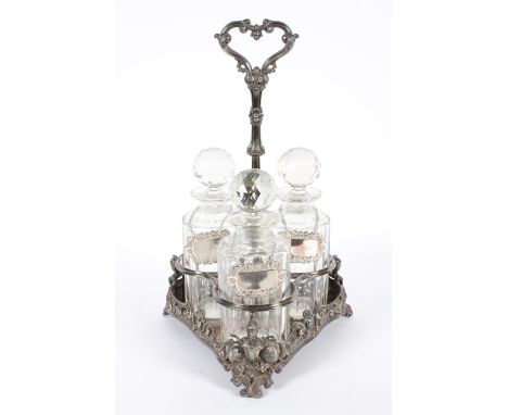 A Victorian silver plated three decanter stand and three glass decanters, the stand of shaped triangular form, rocaille cast,