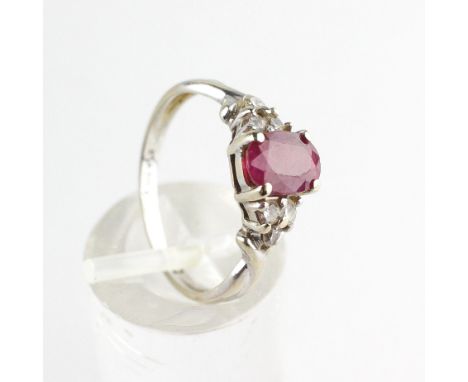 A white metal ring. Principally set with an oval faceted cut ruby stamped to weigh 1.00ct. Finished with a tri of round brill