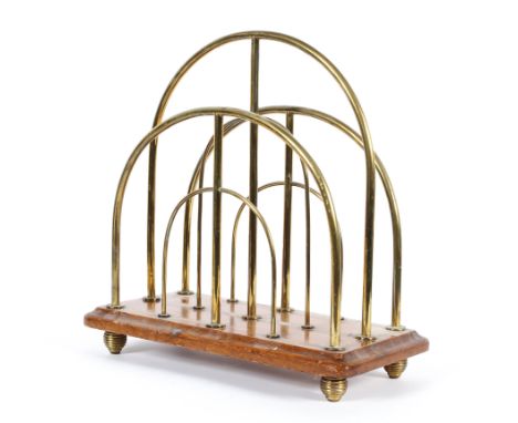 A vintage, mid 20th century brass and wooden-mounted magazine rack, stamped WR &amp; S below a sunburst, with three arched br