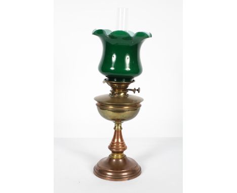 An Edwardian brass oil lamp,with opaque green fluted glass shade above a brass burner and reservoir, on baluster stem and dom