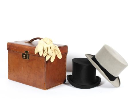 A vintage leather hat case with two top hats, including a Moss Bros. grey top hat (20 cm. wide) and a black collapsible top h