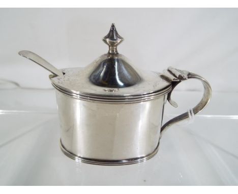 An Edward VII silver hallmarked mustard pot of oval from with blue glass liner and spoon, Chester assay 1919 (pot) and 1907 (