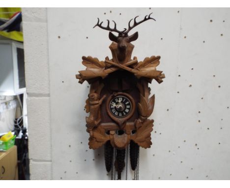 A carved wooden cuckoo clock depicting a rabbit and stags head with three weights and pendulum Est £40 - £60