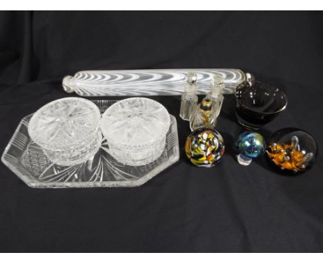 A mixed lot of glassware to include paperweights, vintage glass rolling-pin, cut glass lidded jar, glass bottles and similar