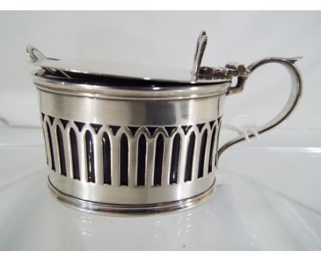 A George V silver hallmarked mustard pot with pierced lancet decoration, blue glass liner and spoon. Chester assay 1919 (pot)