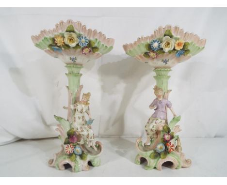 A pair of European ceramic centre-pieces each depicting a maiden and floral decoration, approximately 28 cm (h) (2). Estimate