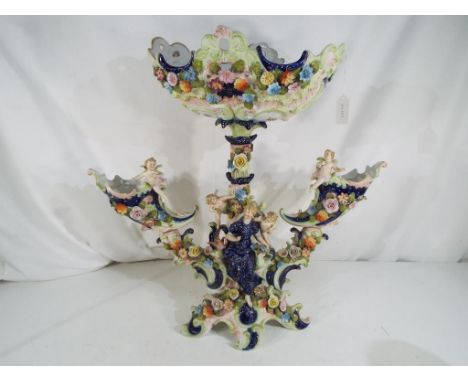 A large European ceramic centre-piece fitted in four sections with detailed floral decoration depicting a maiden surrounded b