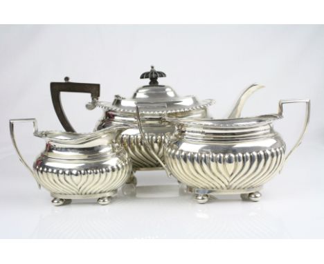 Early 20th century three piece silver tea service, comprising teapot, milk jug and twin handled sugar bowl, each raised on fo