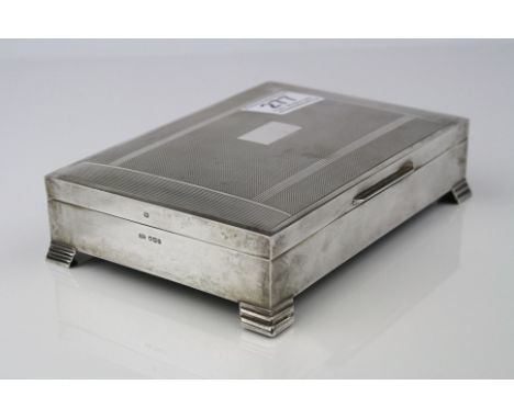 Silver rectangular cigar box raised on four stepped bracket feet, engine turned and banding decoration to hinged lid, rectang