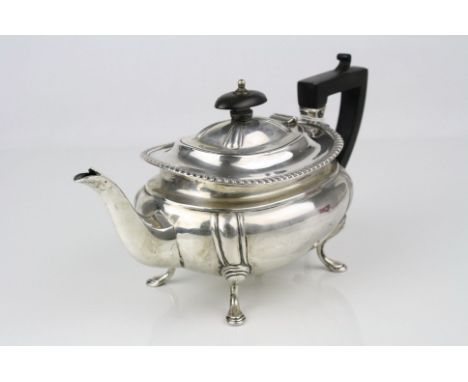 Early 20th century silver bachelor teapot raised on four hoof feet, gadrooning to rim, ebony handle and finial, makers James 