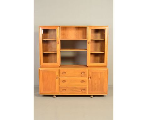 AN ERCOL BLONDE ELM WINDSOR SIDEBOARD/BOOKCASE, model 455D, the top section flanked by two glazed bookcases adjoined by an op