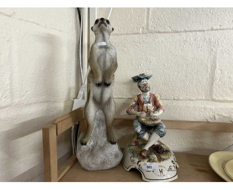 Resin model of a meerkat and a pottery figure of a seated fisherman