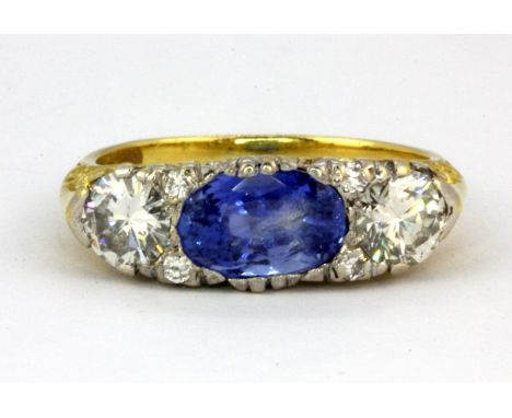 A yellow metal (tested 18ct gold) ring set with oval cut sapphire and brilliant cut diamonds, approx. 2.6ct sapphire and 1.10