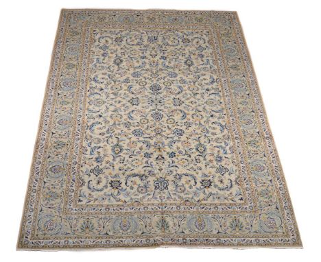 A Kashan carpet, the pale field decorated with an overall design of flowers and scrolling branches, within a similar border d