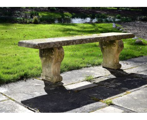 A Regency carved stone garden bench, early 19th century, the rectangular section seat on twin scrolled legs, approximately 53