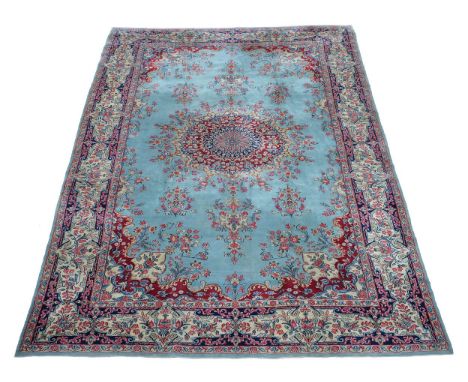 A Kirman carpet, the powder blue field centred by a blue and claret medallion issuing floral branches, cornered by floral dec