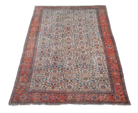 †A Feraghan carpet, the cream field decorated with an overall design of flowering foliage, within madder borders decorated wi