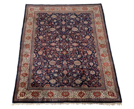 A Sarouk carpet, the navy central field with scrolling flowerhead pattern, within a cream border incorporating madder flowerh