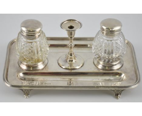 A large Edwardian silver partners inkstand with central taper stick flanked by two cut glass wells, hallmarked Sheffield 1909