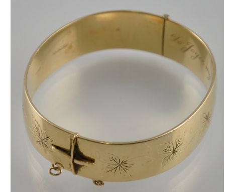 An engraved gold plated hinged bangle 