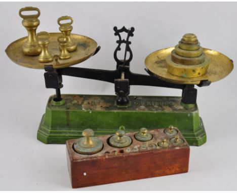 A set of vintage five kilo balance scales on green enamelled cast iron base, with three various sets of brass weights